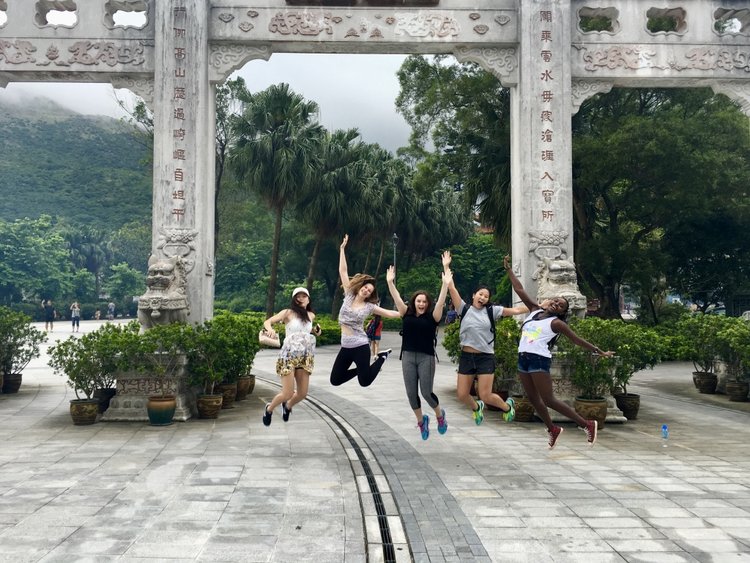 Happy tourists jump near a stone arch.