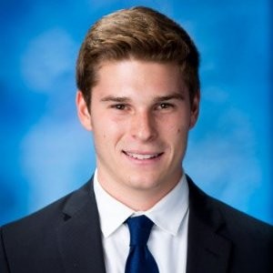 Here's a concise alt tag for the image: `Headshot of a young man in a suit`