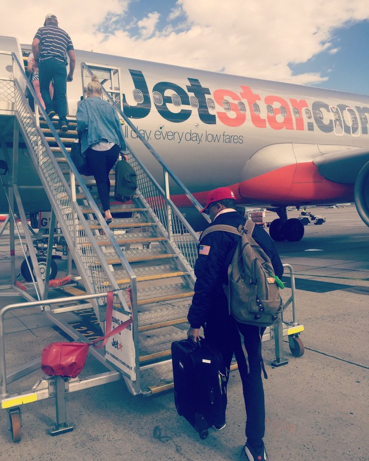 A jetstar plane is boarding passengers on the tarmac.
