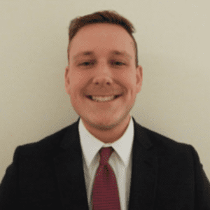 A man in a suit and tie smiling for the camera.