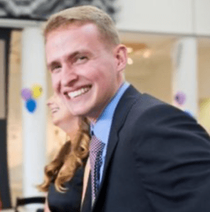 A man in suit and tie smiling for the camera.