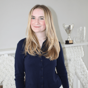 Smiling person standing near trophy display.