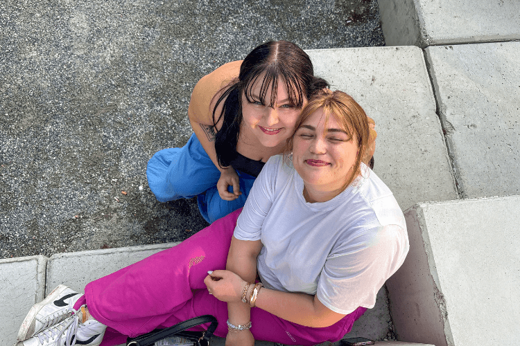 Two smiling women sitting on concrete steps.