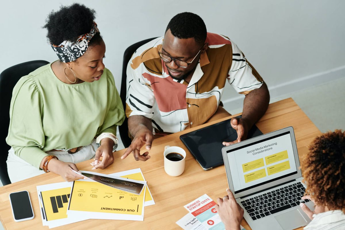 Two people sitting at a table with papers and laptops.