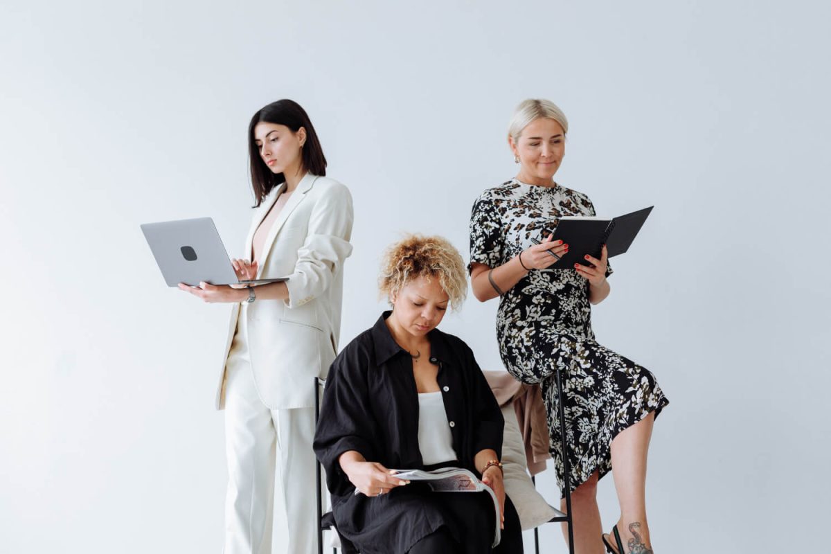 Three women are sitting in a row with laptops.